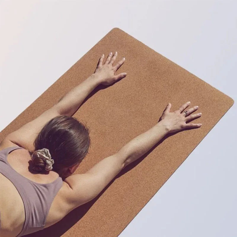 Person practicing yoga on a cork mat with a plain background